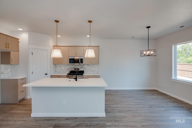 kitchen with hanging light fixtures, light brown cabinetry, tasteful backsplash, and appliances with stainless steel finishes