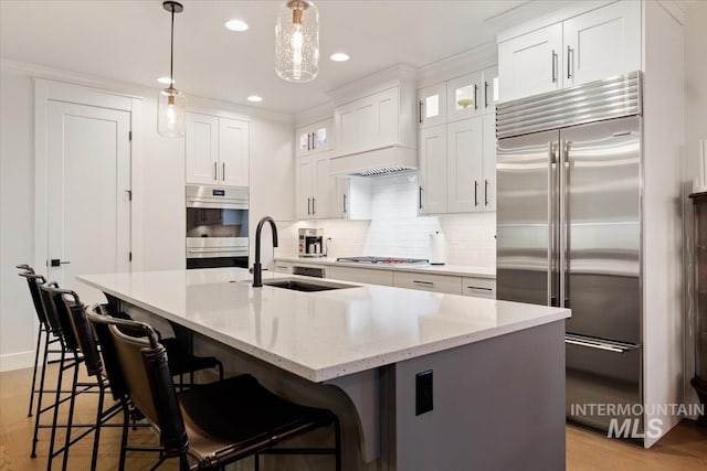 kitchen with a sink, decorative backsplash, white cabinets, and stainless steel appliances