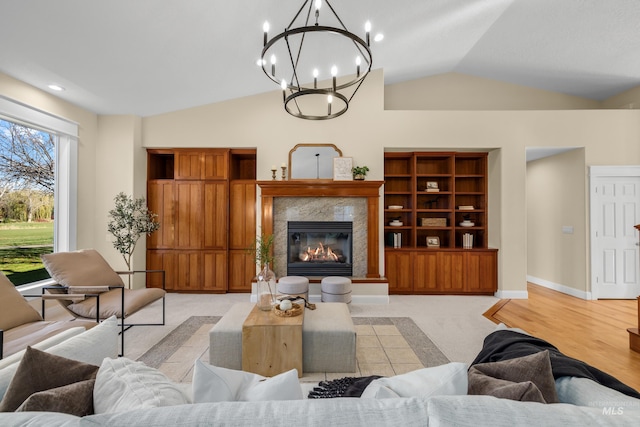 living room with a fireplace, light hardwood / wood-style floors, an inviting chandelier, and vaulted ceiling