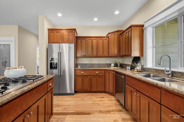 kitchen with light wood-type flooring, stainless steel appliances, sink, and light stone countertops