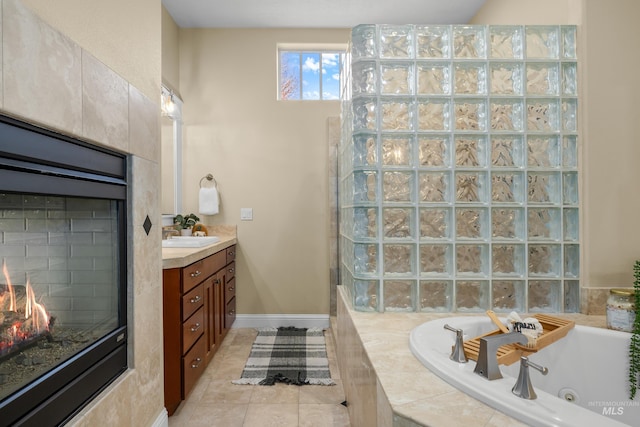 bathroom with tiled bath, a fireplace, vanity, and tile patterned floors