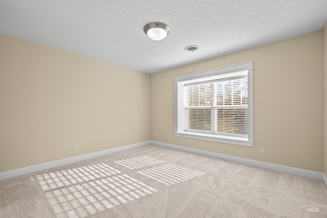 empty room with a textured ceiling and light carpet