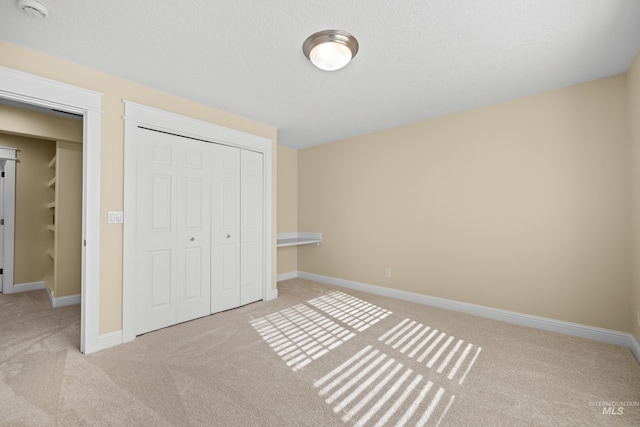 unfurnished bedroom with a textured ceiling, light carpet, and a closet