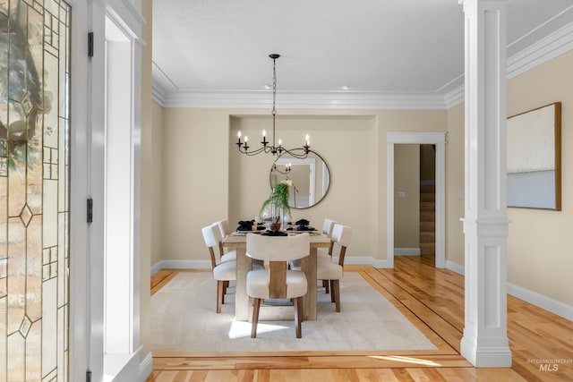 dining room with wood-type flooring, a chandelier, crown molding, and decorative columns