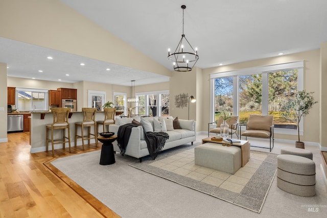 living room featuring light wood-type flooring, high vaulted ceiling, and an inviting chandelier