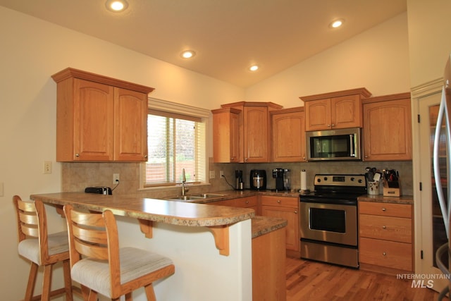 1491 N Millstream Ct, Nampa, ID 83686 - kitchen with appliances with stainless steel finishes, a kitchen bar, a peninsula, vaulted ceiling, and backsplash