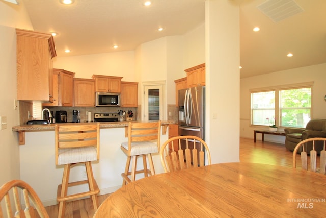 1491 N Millstream Ct, Nampa, ID 83686 - kitchen featuring appliances with stainless steel finishes, a peninsula, light wood finished floors, tasteful backsplash, and recessed lighting