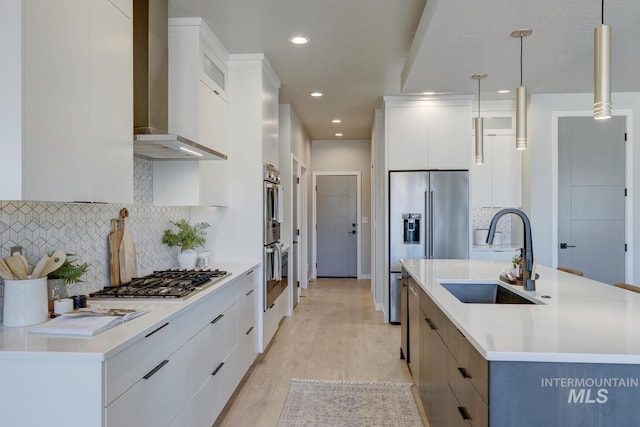 kitchen with wall chimney exhaust hood, modern cabinets, stainless steel appliances, and a sink