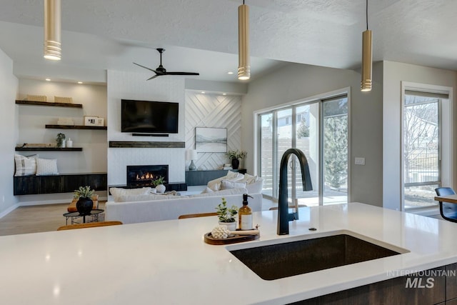 kitchen with a textured ceiling, a fireplace, light countertops, and a sink