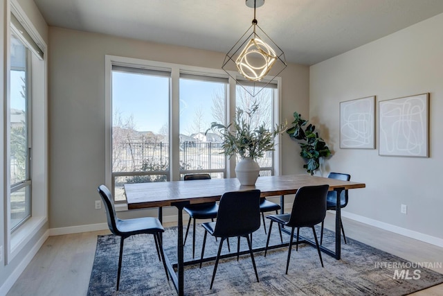 dining space featuring a notable chandelier, baseboards, and wood finished floors