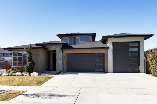 prairie-style house with a garage, stone siding, and driveway