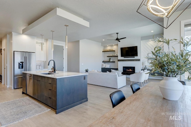 kitchen featuring a fireplace, stainless steel appliances, white cabinets, a sink, and modern cabinets