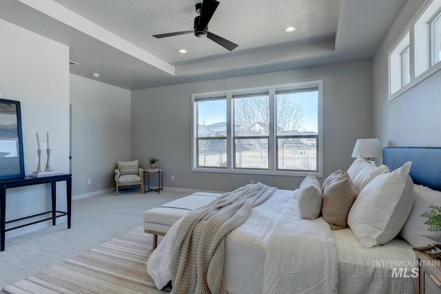 bedroom with baseboards, a tray ceiling, a ceiling fan, and light colored carpet