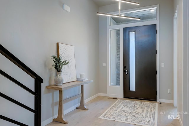 entrance foyer featuring visible vents, stairway, baseboards, and wood finished floors