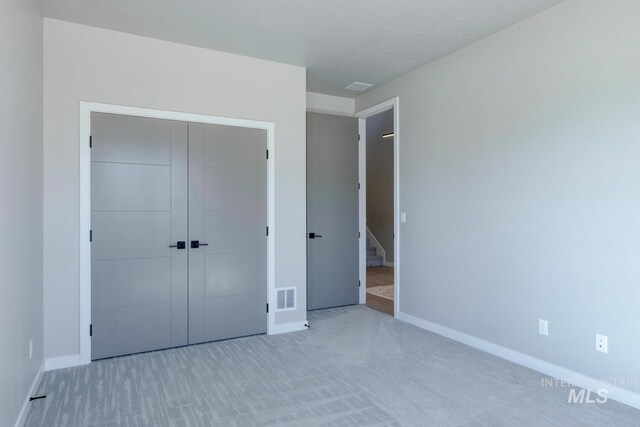 unfurnished bedroom featuring a closet, carpet flooring, visible vents, and baseboards