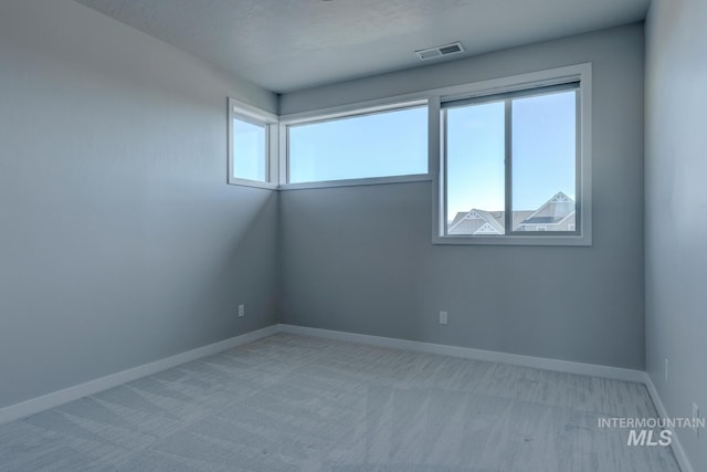 empty room with a healthy amount of sunlight, visible vents, and baseboards