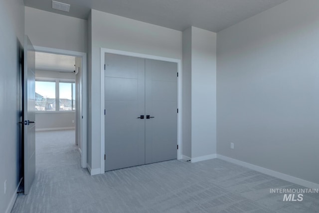 unfurnished bedroom with a closet, carpet, visible vents, and baseboards