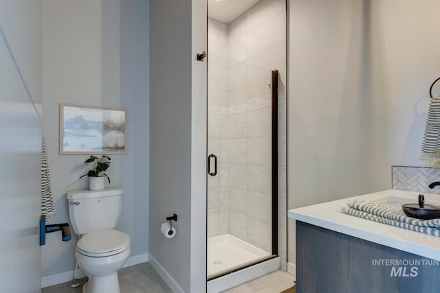 bathroom featuring a stall shower, vanity, toilet, and baseboards