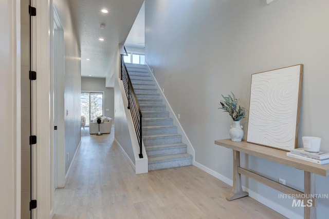 stairway with recessed lighting, baseboards, and wood finished floors