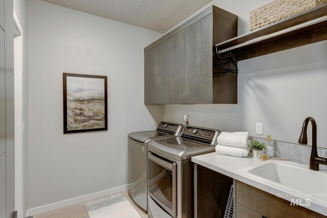 laundry area featuring cabinet space, baseboards, a sink, and washing machine and clothes dryer