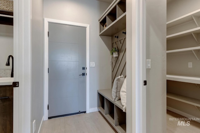 mudroom featuring light wood-type flooring, baseboards, and a sink