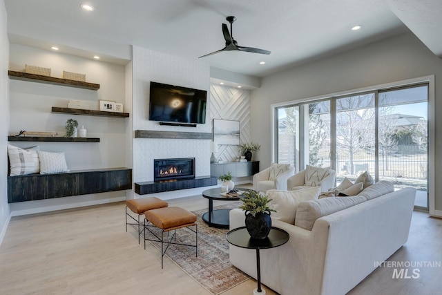 living room with a tile fireplace, recessed lighting, wood finished floors, a ceiling fan, and baseboards