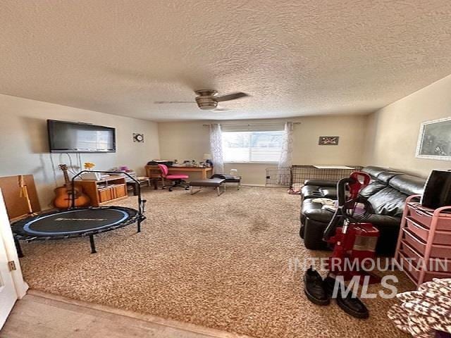 carpeted living room featuring ceiling fan and a textured ceiling