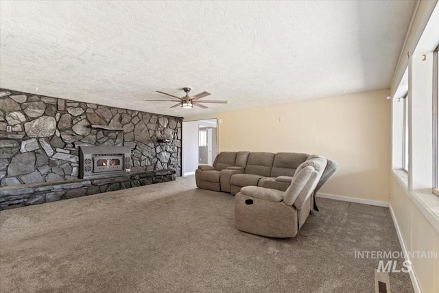 carpeted living room featuring a textured ceiling, a stone fireplace, and ceiling fan