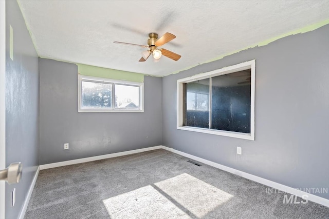 carpeted spare room with ceiling fan and a textured ceiling