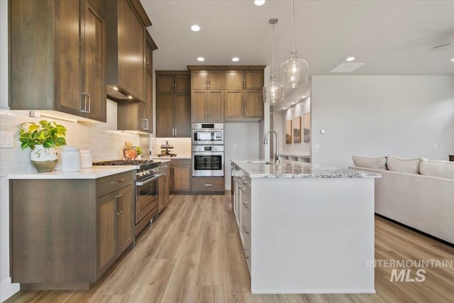 8469 W Happy Day Dr, Meridian, ID 83646 - kitchen featuring stainless steel appliances, a sink, open floor plan, light wood-type flooring, and pendant lighting