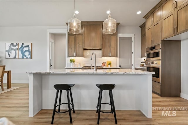 8469 W Happy Day Dr, Meridian, ID 83646 - kitchen with tasteful backsplash, light wood-style flooring, a sink, baseboards, and recessed lighting