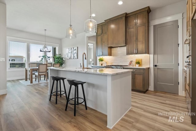 8469 W Happy Day Dr, Meridian, ID 83646 - kitchen featuring a sink, decorative backsplash, light wood-style floors, recessed lighting, and an island with sink