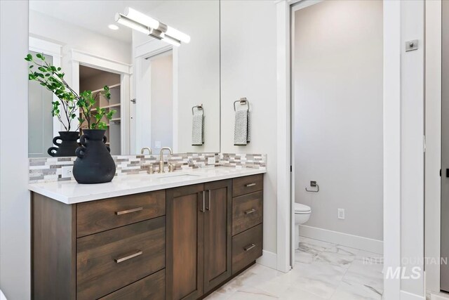 8469 W Happy Day Dr, Meridian, ID 83646 - bathroom featuring toilet, marble look tiles, decorative backsplash, and baseboards