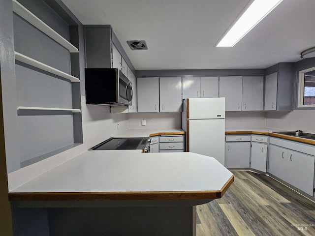 kitchen with visible vents, open shelves, range with electric stovetop, freestanding refrigerator, and light countertops