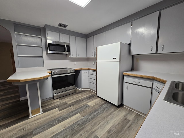 kitchen with stainless steel appliances, dark wood-type flooring, light countertops, and a sink