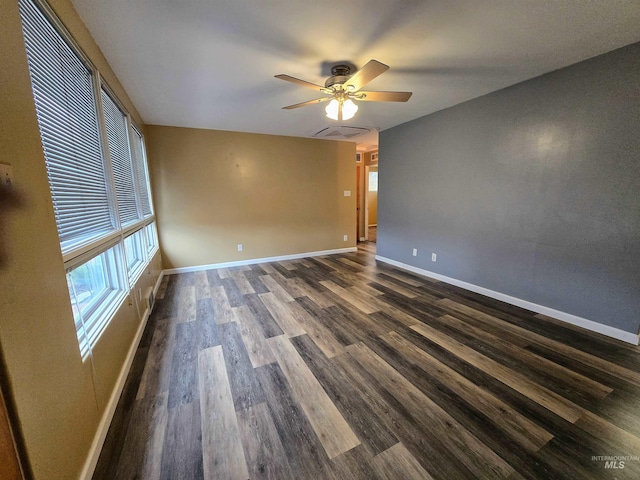 empty room with ceiling fan, visible vents, baseboards, and dark wood finished floors