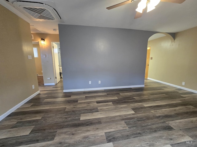 unfurnished room with wood finished floors, arched walkways, visible vents, and baseboards