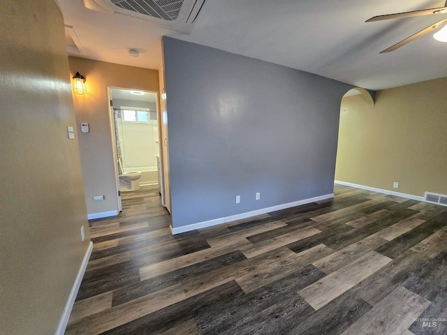 empty room featuring dark wood-style floors, arched walkways, visible vents, and ceiling fan