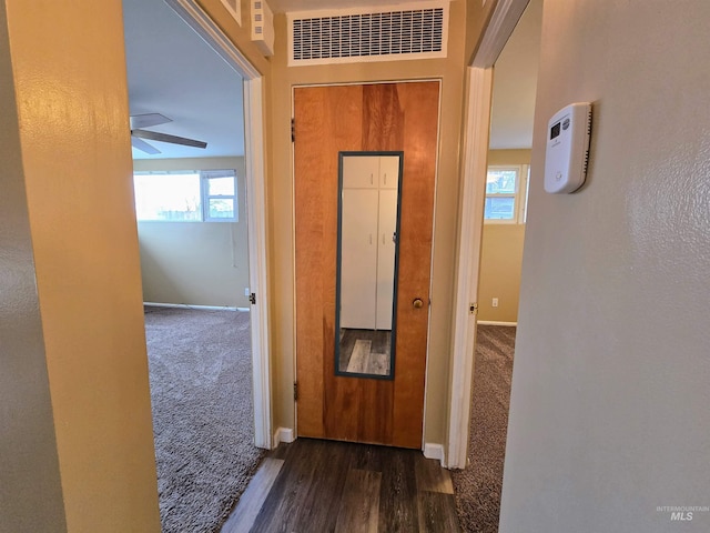 corridor featuring wood finished floors, baseboards, visible vents, and carpet floors