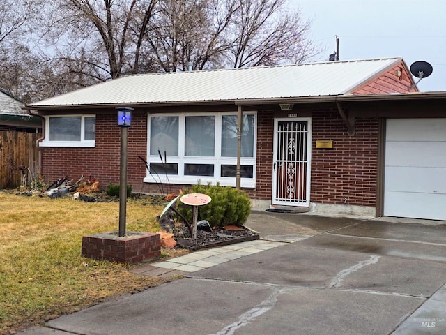 ranch-style house with brick siding, an attached garage, metal roof, and a front lawn