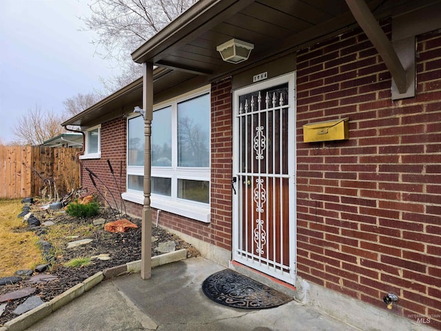 property entrance featuring brick siding and fence