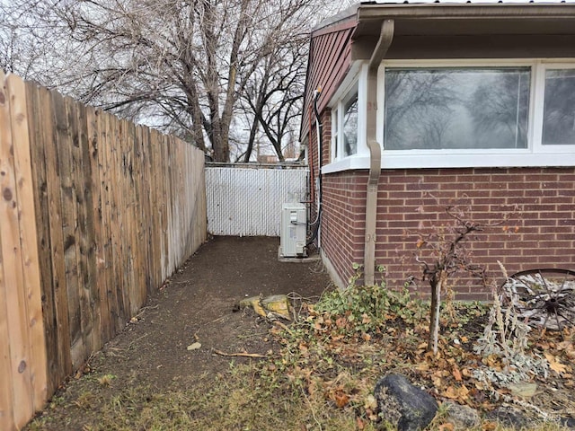 view of property exterior with ac unit, a fenced backyard, and brick siding