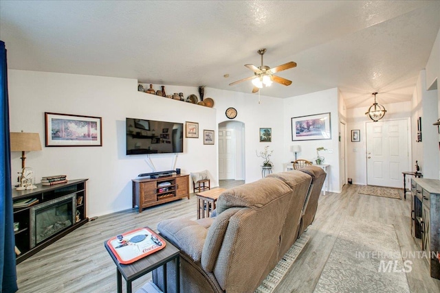 living room featuring ceiling fan with notable chandelier, lofted ceiling, and light hardwood / wood-style flooring