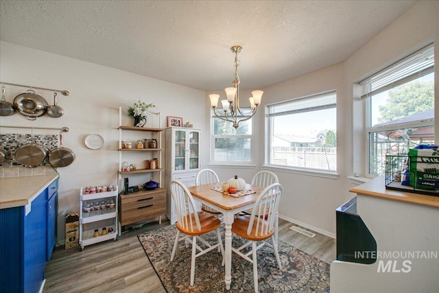 dining room featuring a textured ceiling, hardwood / wood-style floors, and a chandelier