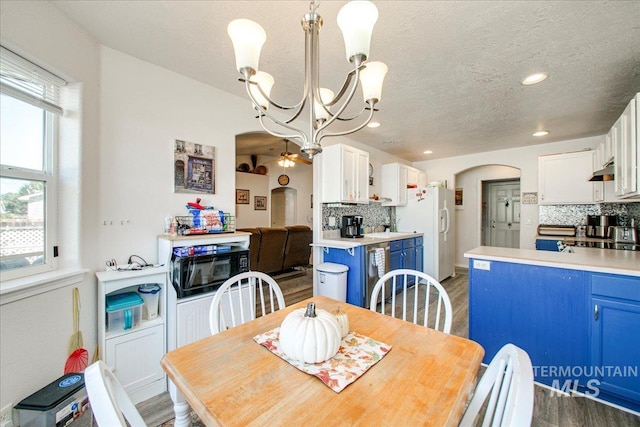 dining room with ceiling fan with notable chandelier, beverage cooler, a textured ceiling, and dark wood-type flooring