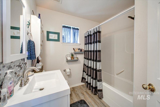 bathroom featuring wood-type flooring, vanity, shower / bath combo with shower curtain, and decorative backsplash