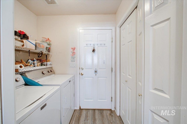 clothes washing area featuring washer and clothes dryer and light hardwood / wood-style floors