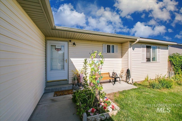 view of exterior entry featuring a yard and a patio area