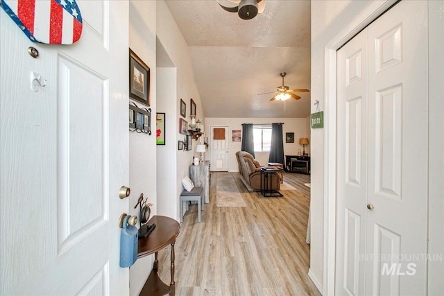 entryway featuring a textured ceiling, lofted ceiling, ceiling fan, and light hardwood / wood-style flooring