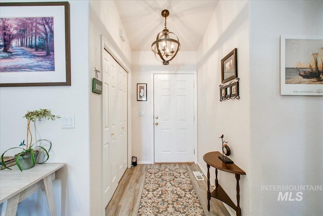 entrance foyer with light wood-type flooring, lofted ceiling, and an inviting chandelier